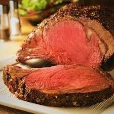 A large piece of roast beef is sitting on a white plate with a fork.