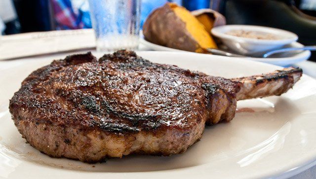 A close up of a steak on a white plate on a table.