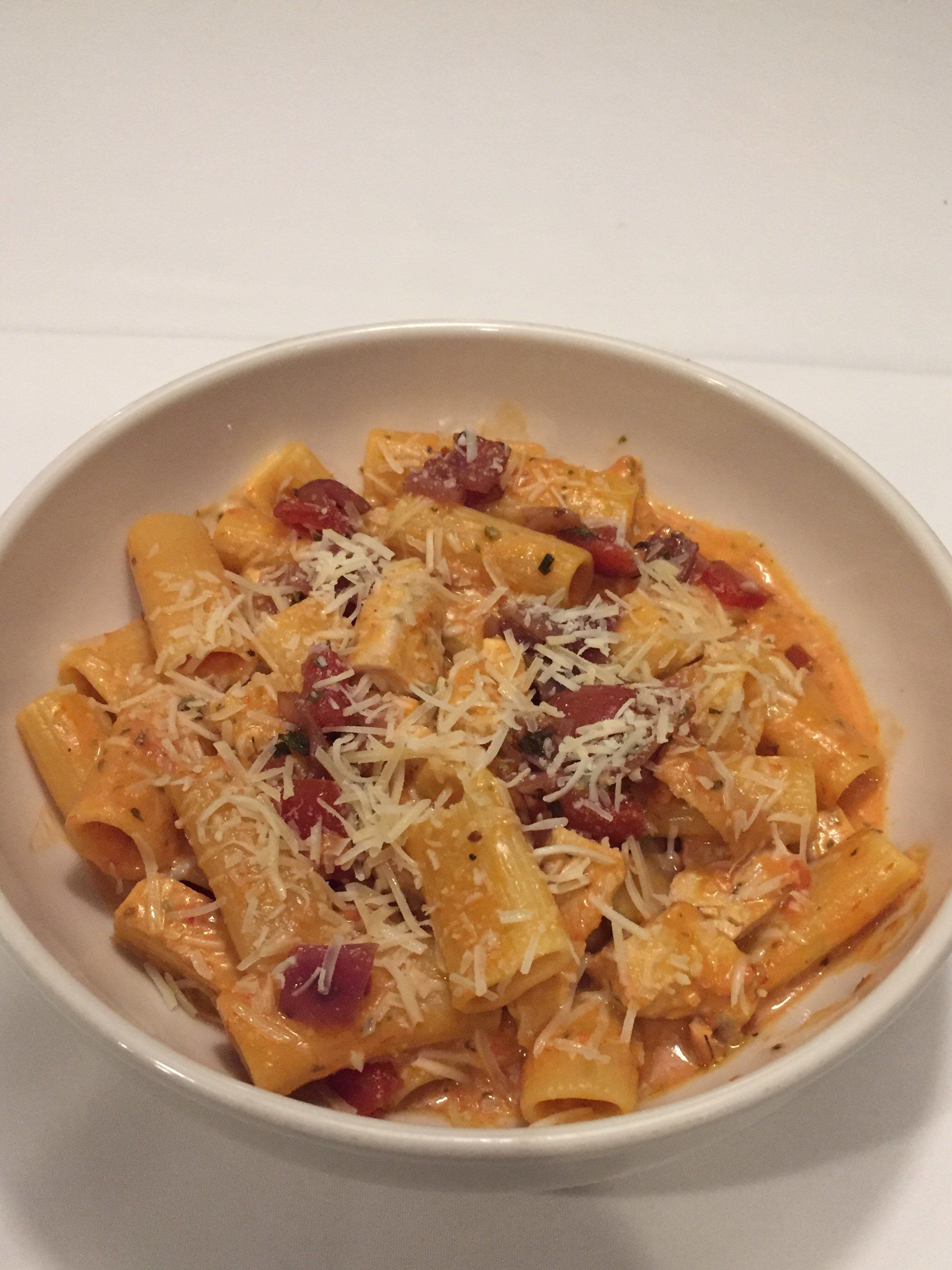 A bowl of pasta with sauce and cheese on a table.