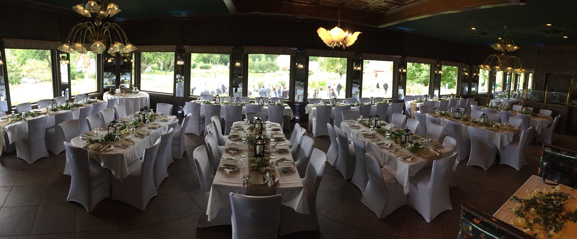 A large room filled with tables and chairs set up for a wedding reception.