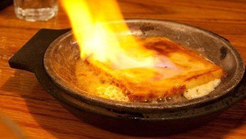 A piece of food is being cooked in a pan with flames coming out of it.