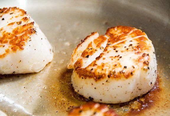 Two scallops are being cooked in a pan.