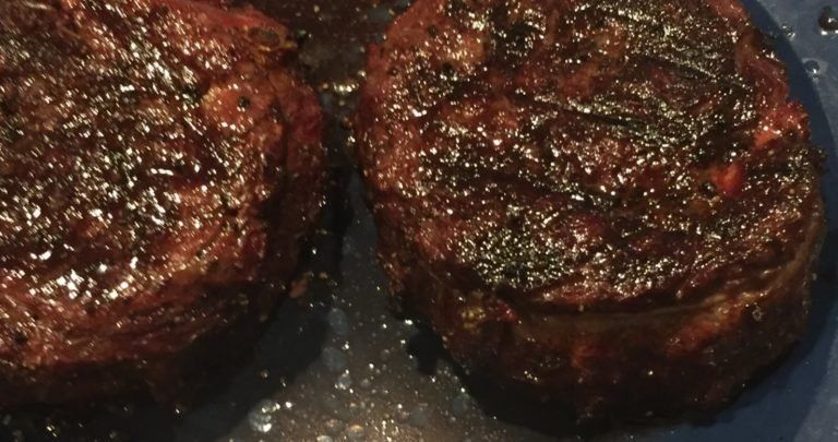 A close up of two steaks on a blue plate.