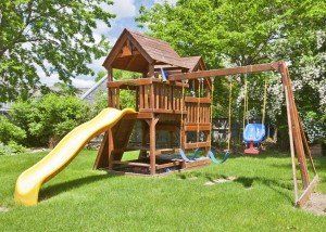 Back Yard Wooden Swing Set on Green Lawn