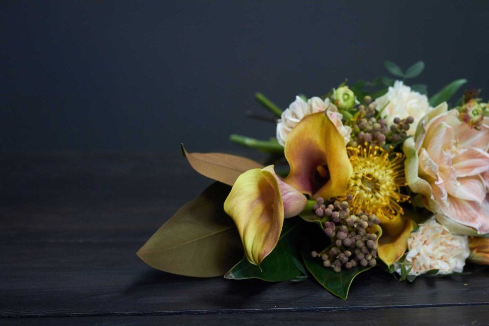 Mazzo di fiori gialli e pesca su una superficie di legno scuro.