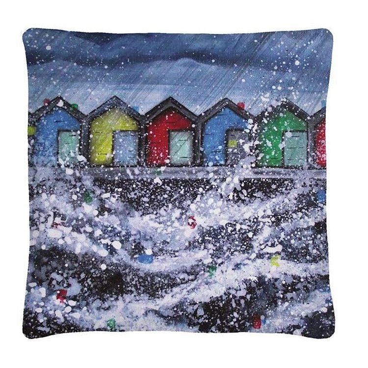 Snowy row of colorful beach huts under a dark winter sky.