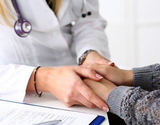 Doctor Holds Patient Hand — Independent Insurance Agency in Forest City, NC A caring touch with a person seeking the best life insurance plan for Salisbury, NC