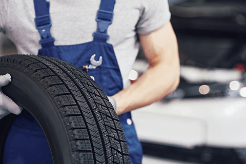 Worker Holding Black Tire — Monroe, NC — Small Bros. Tire Co Inc. Worker Holding Black Tire — Monroe, NC — Small Bros. Tire Co Inc.
