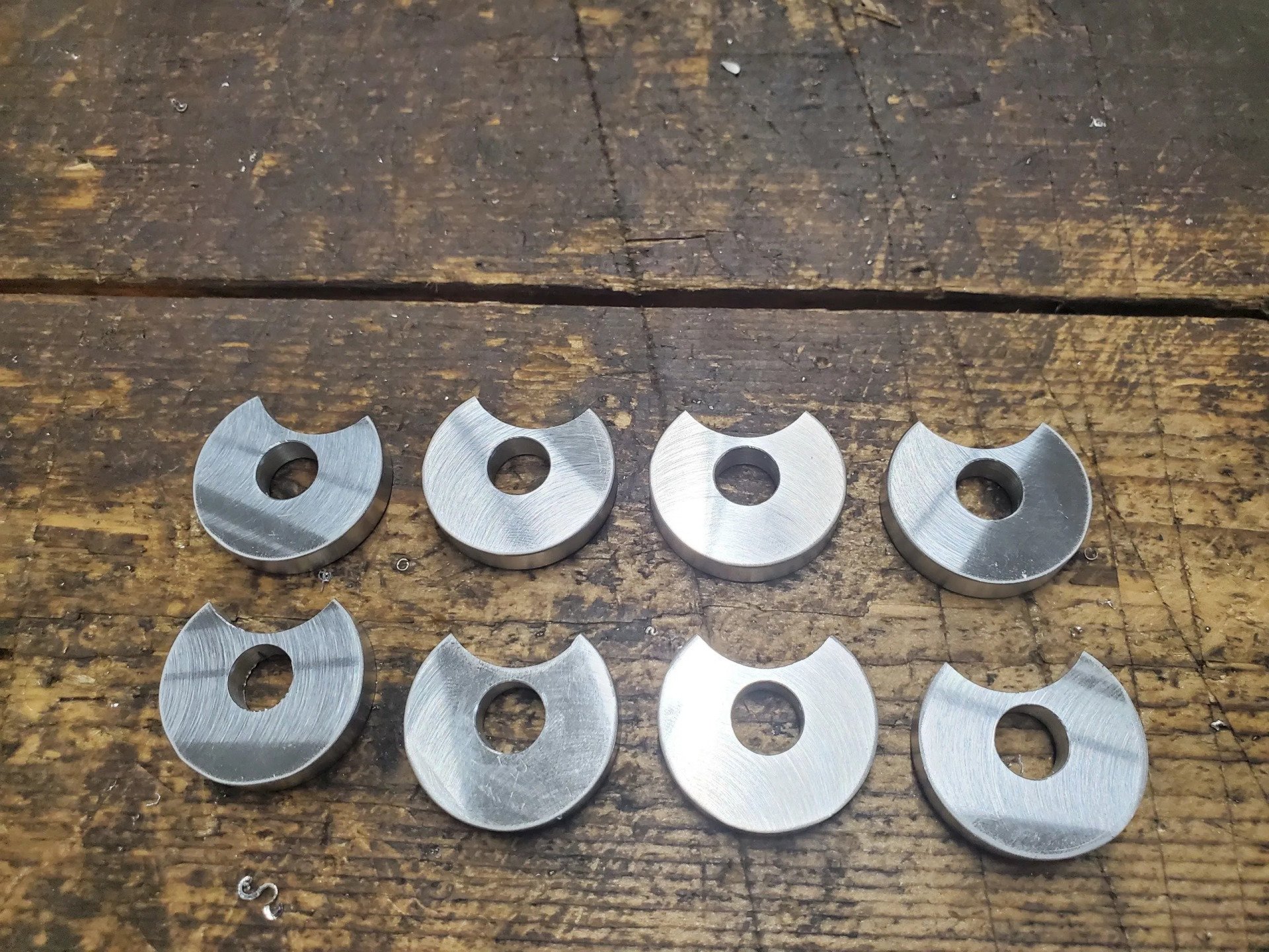 A bunch of metal pieces with holes in them on a wooden table