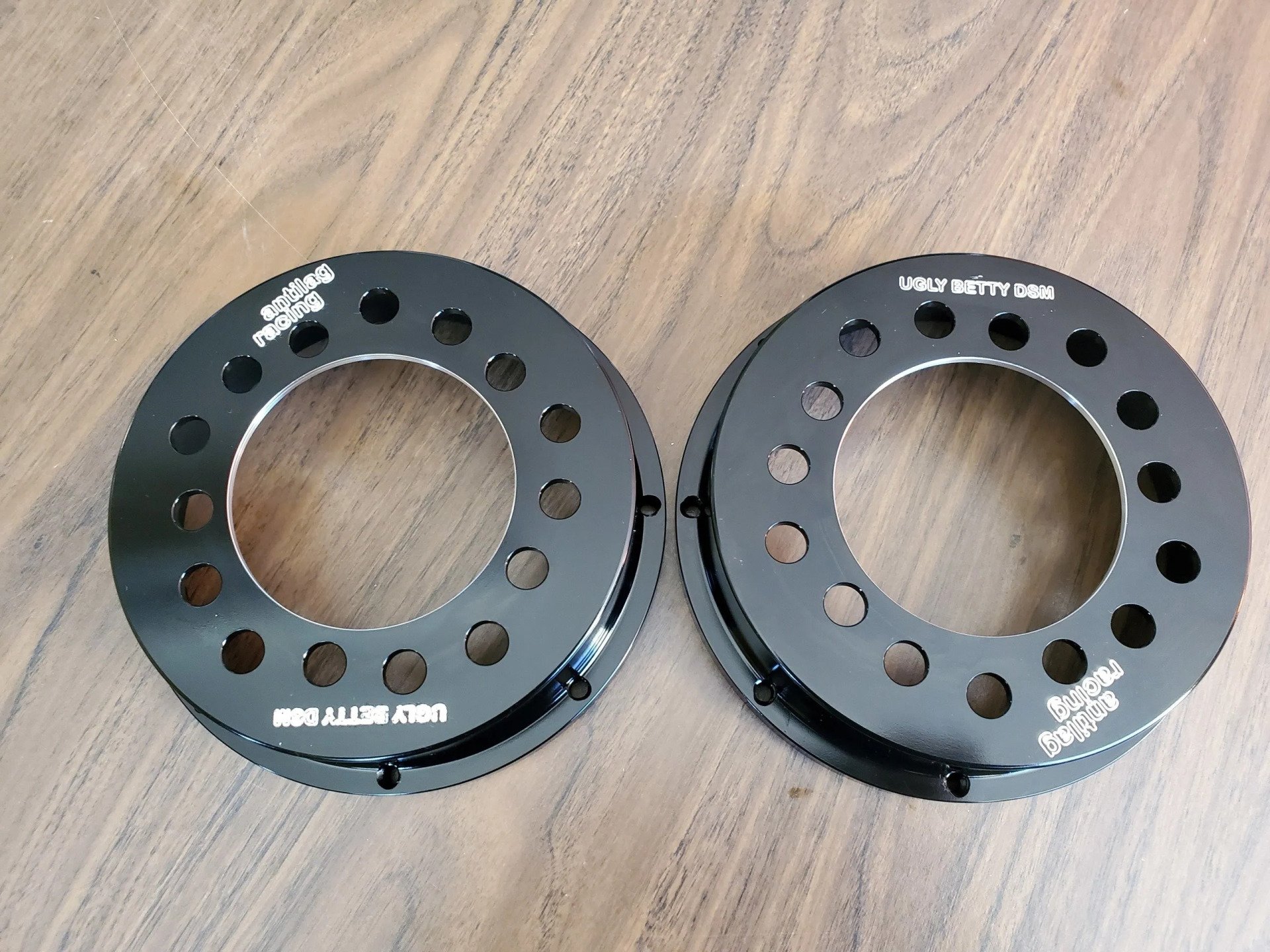A pair of black rings with holes in them on a wooden table
