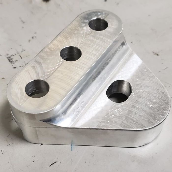 A piece of metal with three holes in it is sitting on a table.