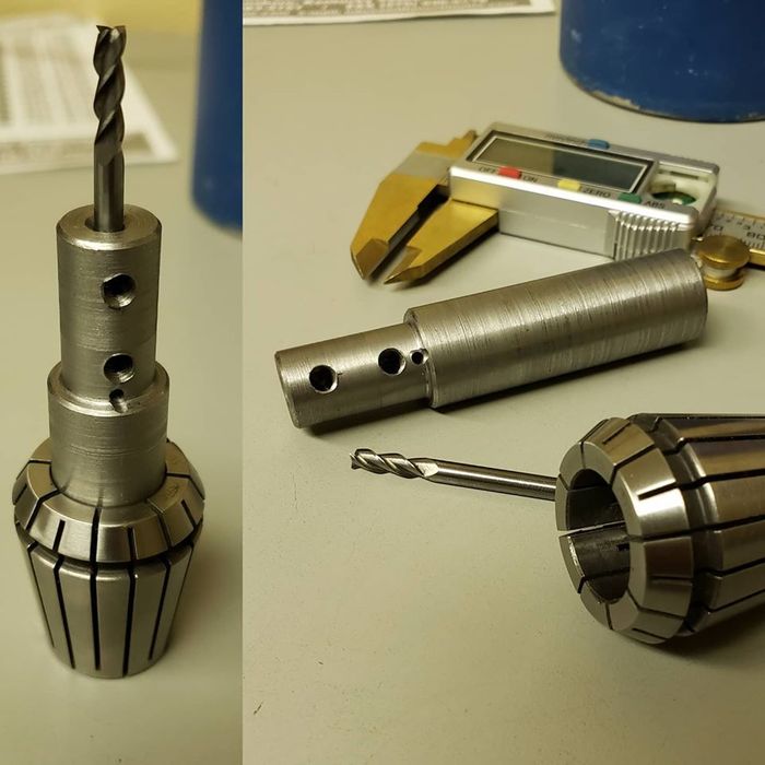 A drill bit is sitting on a table next to a caliper