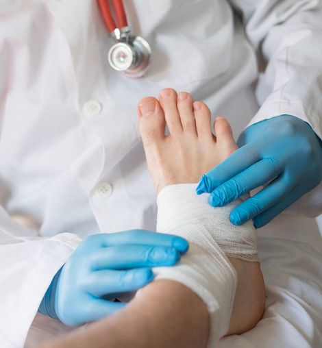 Doctor Bandaging Injured Foot — Longmeadow, MA — Dr. Christopher H. Peteros, DPM, LLC Doctor Bandaging Injured Foot — Longmeadow, MA — Dr. Christopher H. Peteros, DPM, LLC