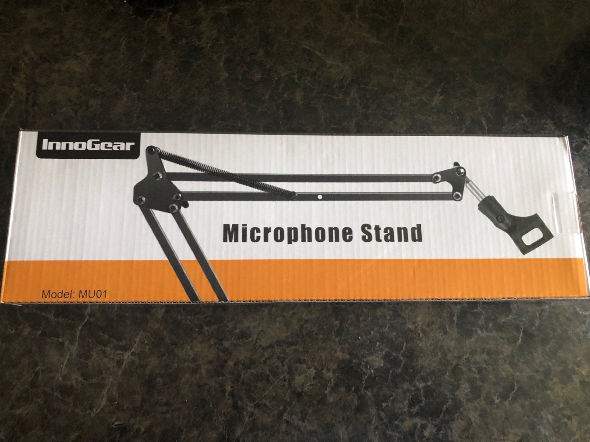 A microphone stand is in a box on a table.