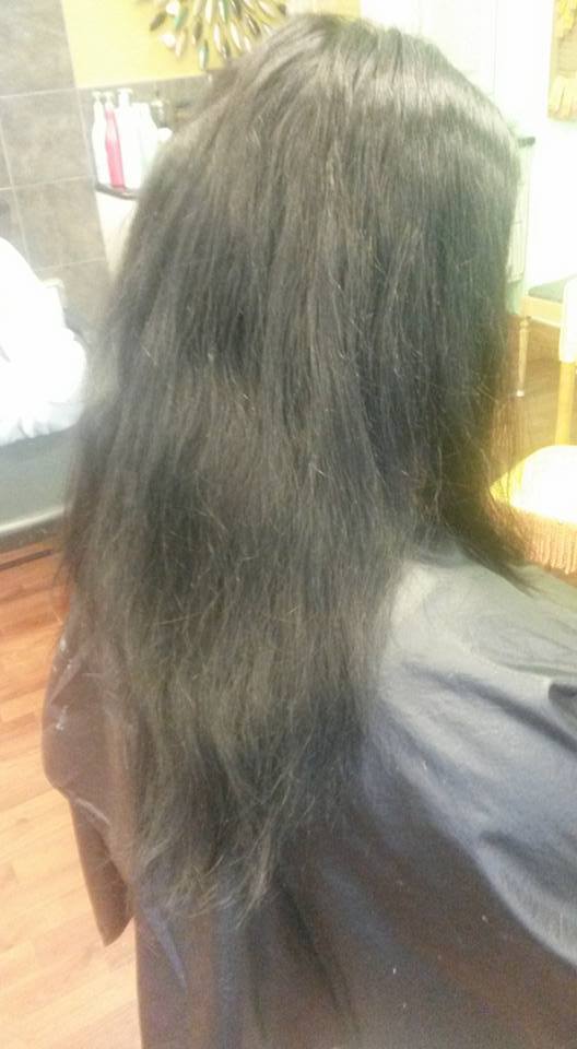 A woman with long black hair is sitting in a chair in a salon.