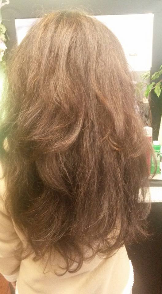 A woman with long brown hair is standing in front of a mirror.