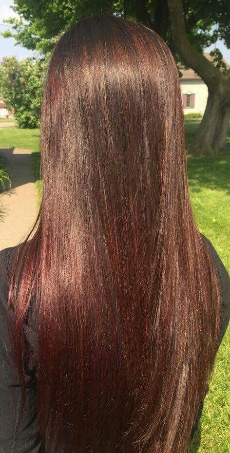 A woman with long brown hair is standing in a park.