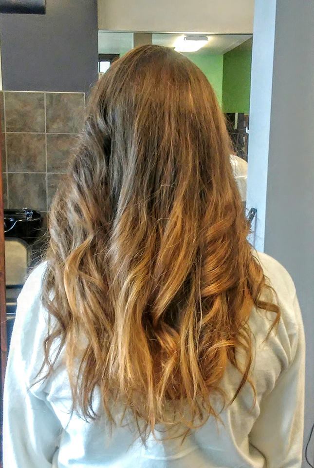 A woman with long curly hair is standing in front of a mirror.