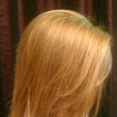 A close up of a woman's blonde hair against a dark background.