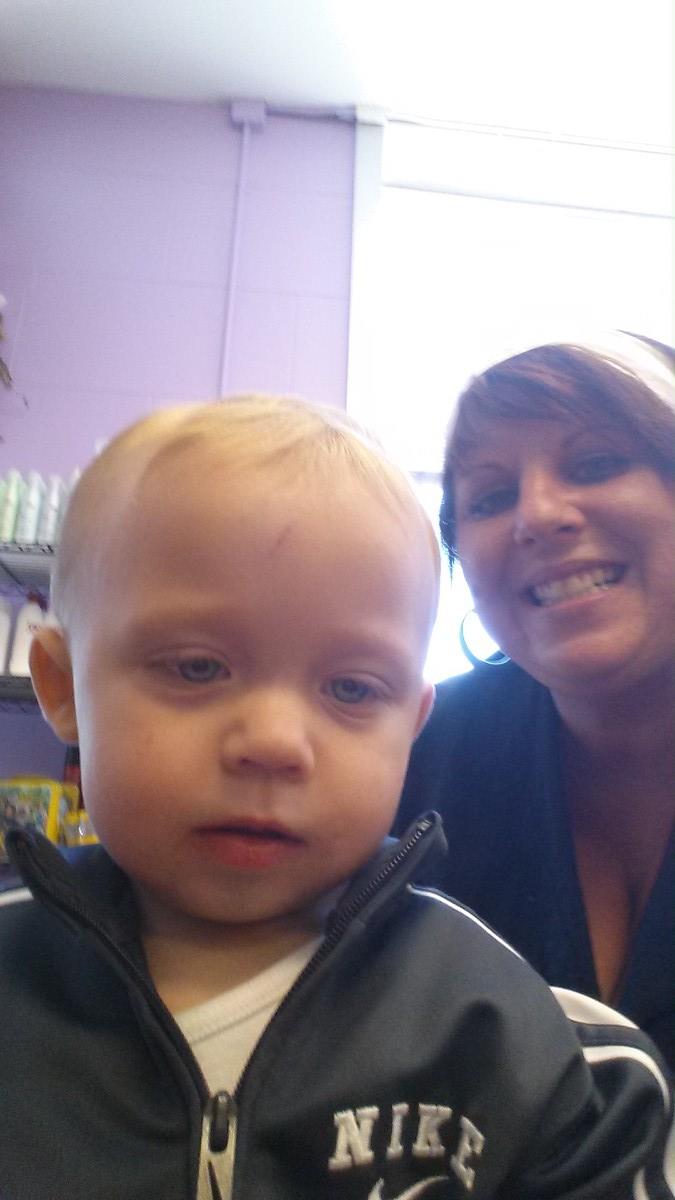 A woman is smiling next to a baby wearing a Nike jacket.