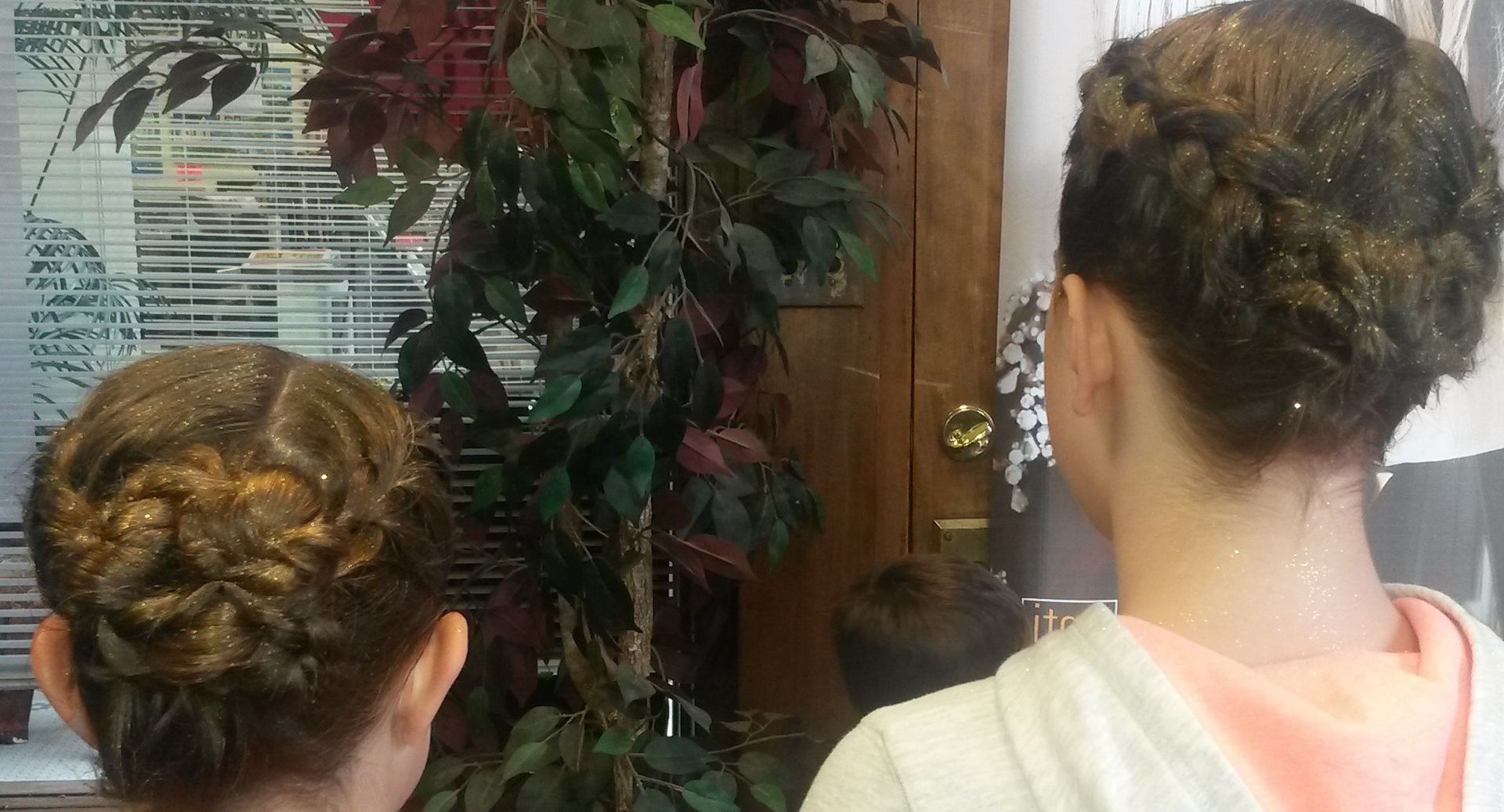 Two women are standing next to each other with their hair in a bun.