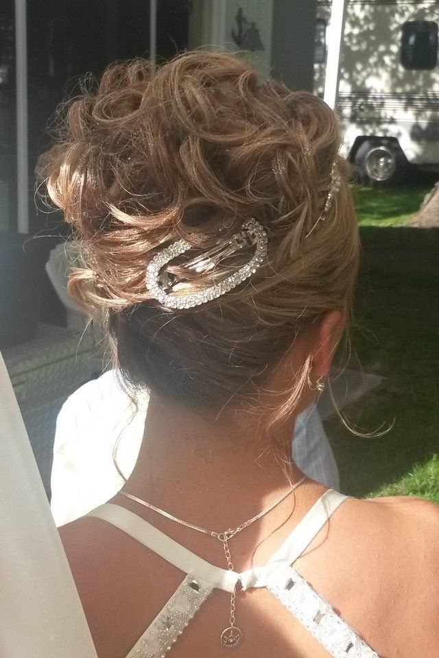A woman in a white dress is wearing a bun and a necklace.