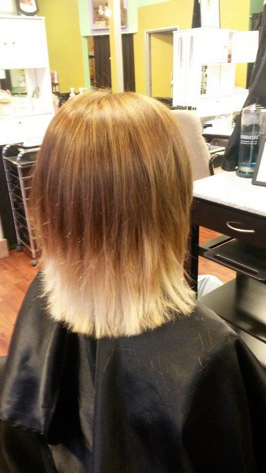 A woman with highlights is getting her hair cut in a salon.