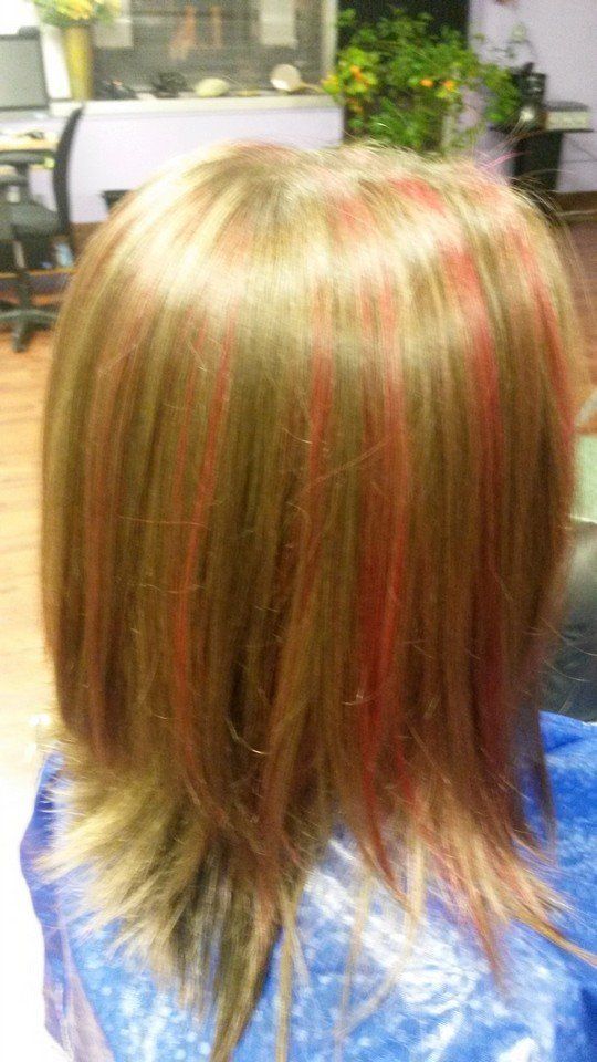 A woman with red highlights in her hair is sitting in a chair.
