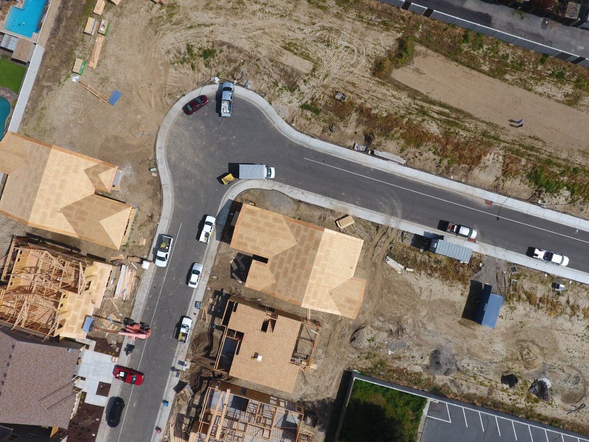 The first image is of a brand new residential neighborhood that is still under construction. Lots of dirt lots and partially built homes, but asphalt has already been paved. The second image is of a family--a man, wife, two children and their grandmother--sitting on the curb in their neighborhood..