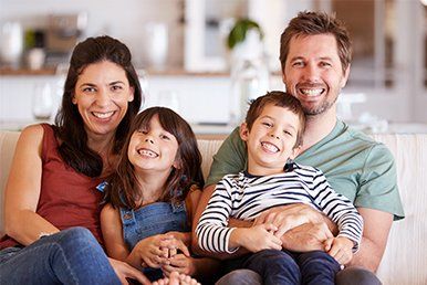 Happy Family Sitting on a Sofa — White Bear Lake, MN — Reibel Heating & Air Conditioning Happy Family Sitting on a Sofa — White Bear Lake, MN — Reibel Heating & Air Conditioning