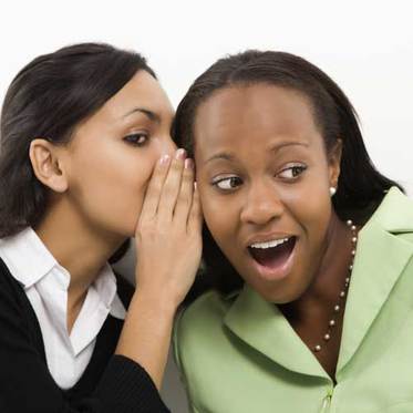 woman whisper into woman's ear