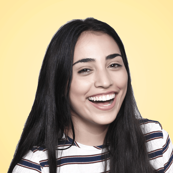 Woman with long dark hair smiles widely, wearing a striped shirt against a yellow background.