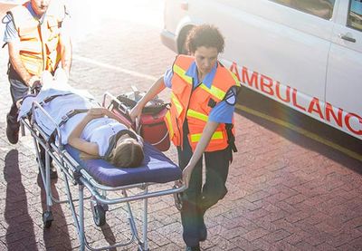 Woman laying down a table while paramedics  pull it