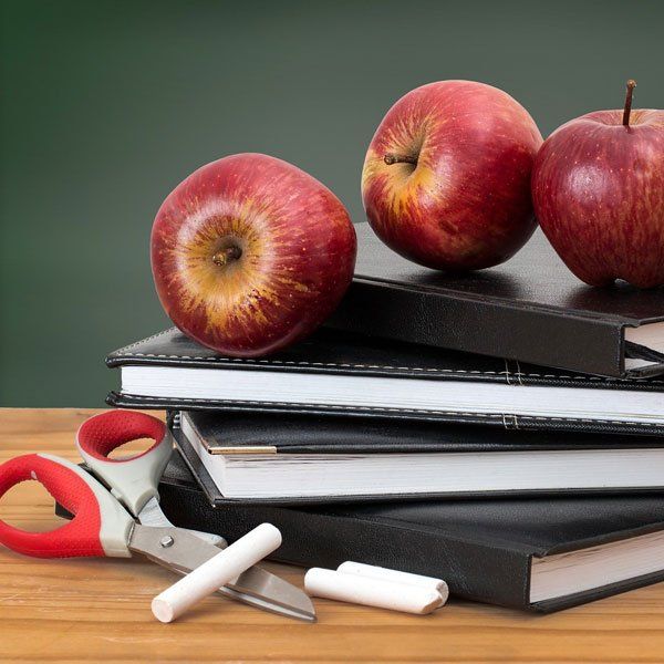 Three apples are sitting on top of a stack of books