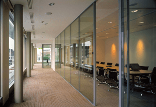 For partition installation in Newcastle call 01912 677194 office hallway with windows to the left and glass partitions to the right and table and chairs