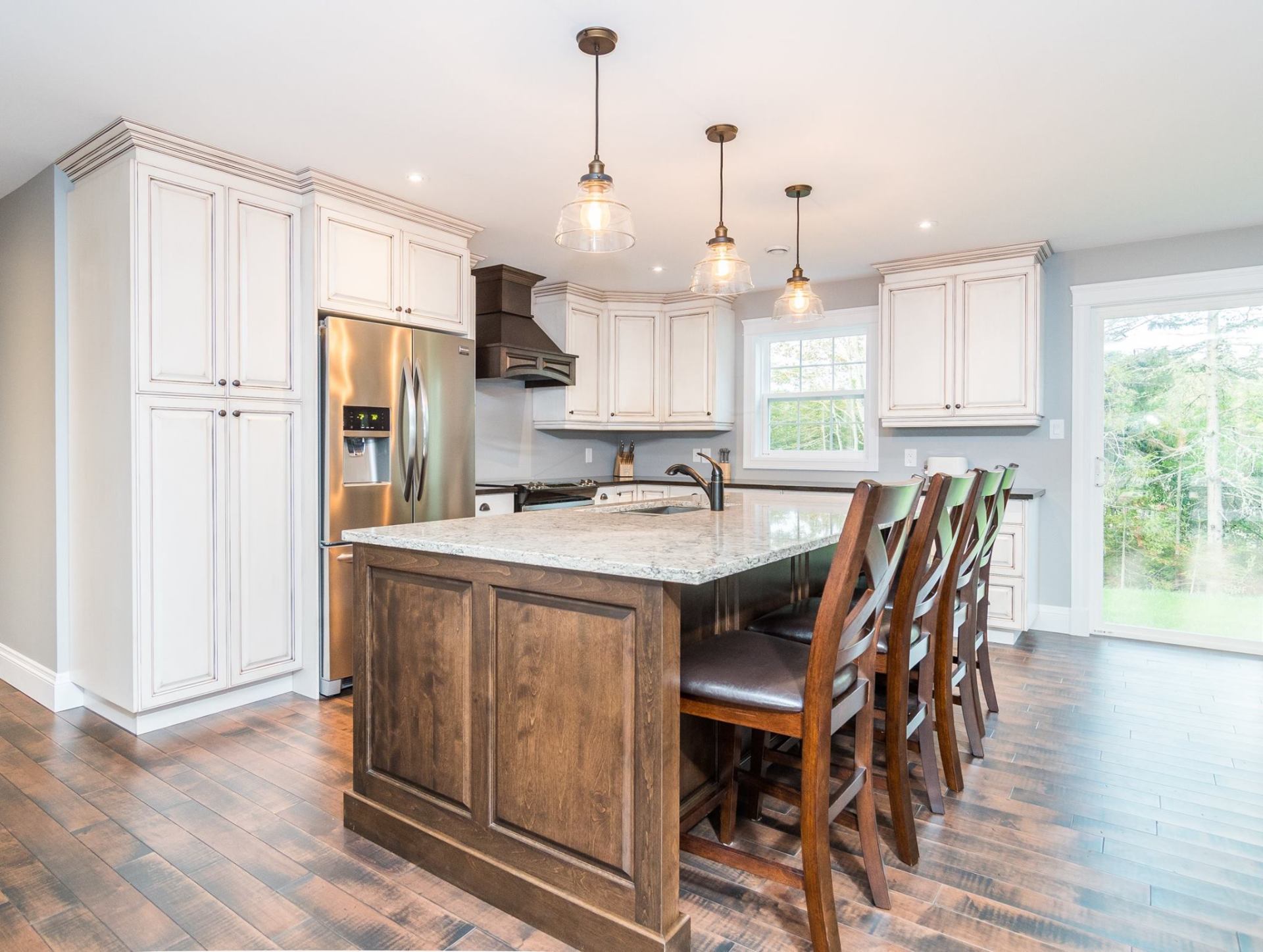 Modern kitchen featuring white cabinets, a dark wood island with granite countertop, stainless steel appliances, and wood.