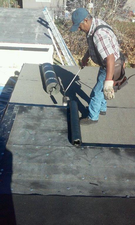 a man is working on a roof with a roller .