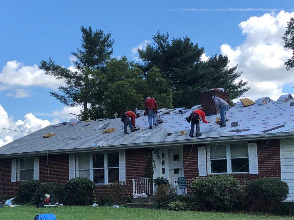 a group of people are working on the roof of a house .