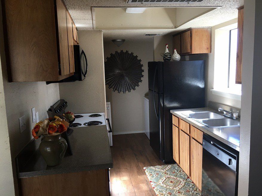 Kitchen with wooden cabinets, black appliances, and a window.