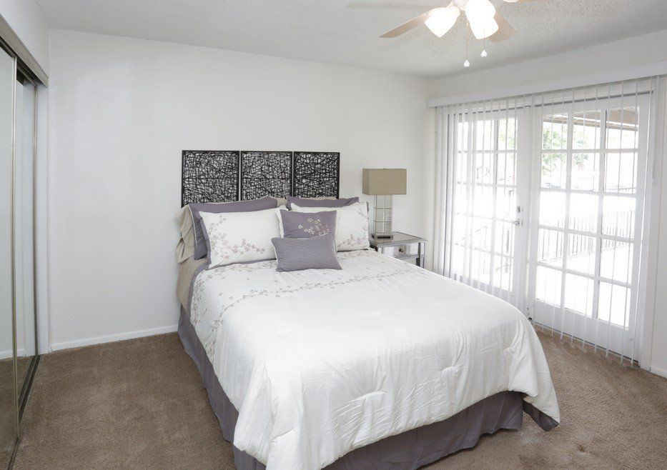 Bedroom with bed, headboard, mirrored closet door, and glass doors to a patio.