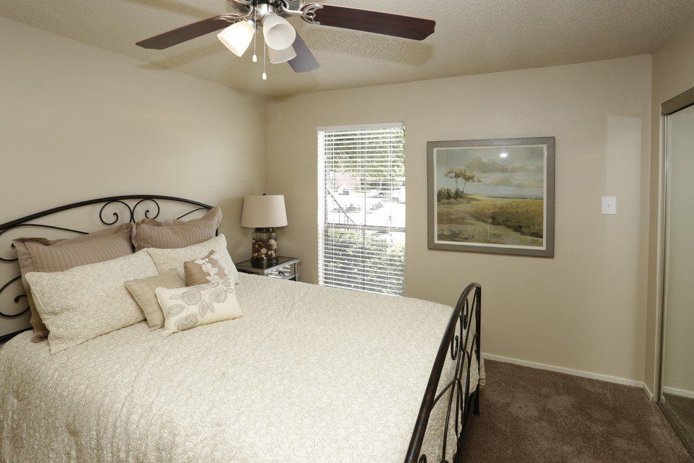 Bedroom with bed, nightstand, window, art, ceiling fan, and sliding closet door.