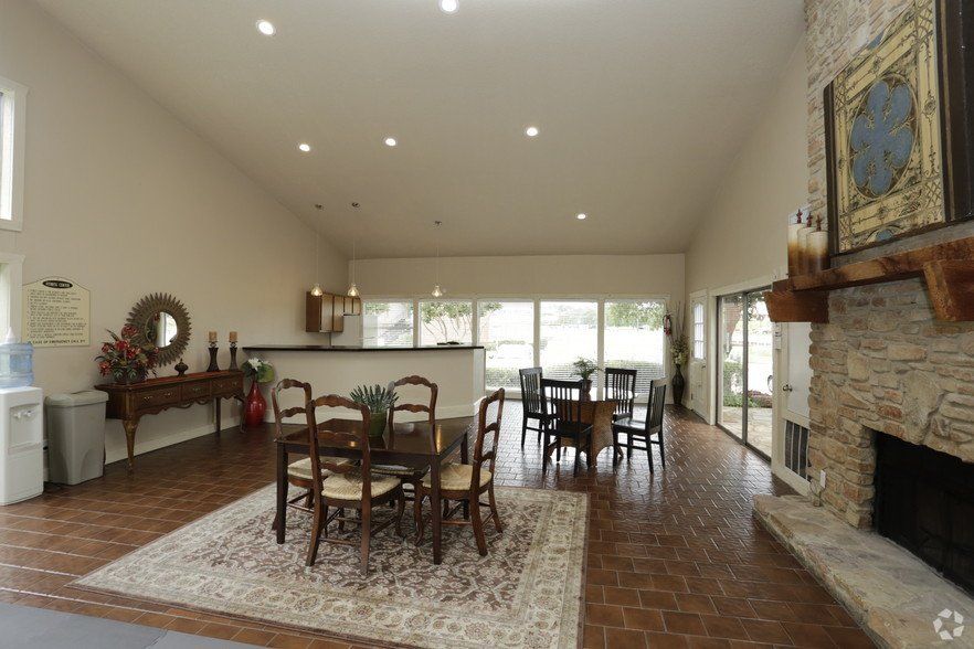 Spacious room with dining tables, fireplace, and bar area. Large windows, neutral color scheme.