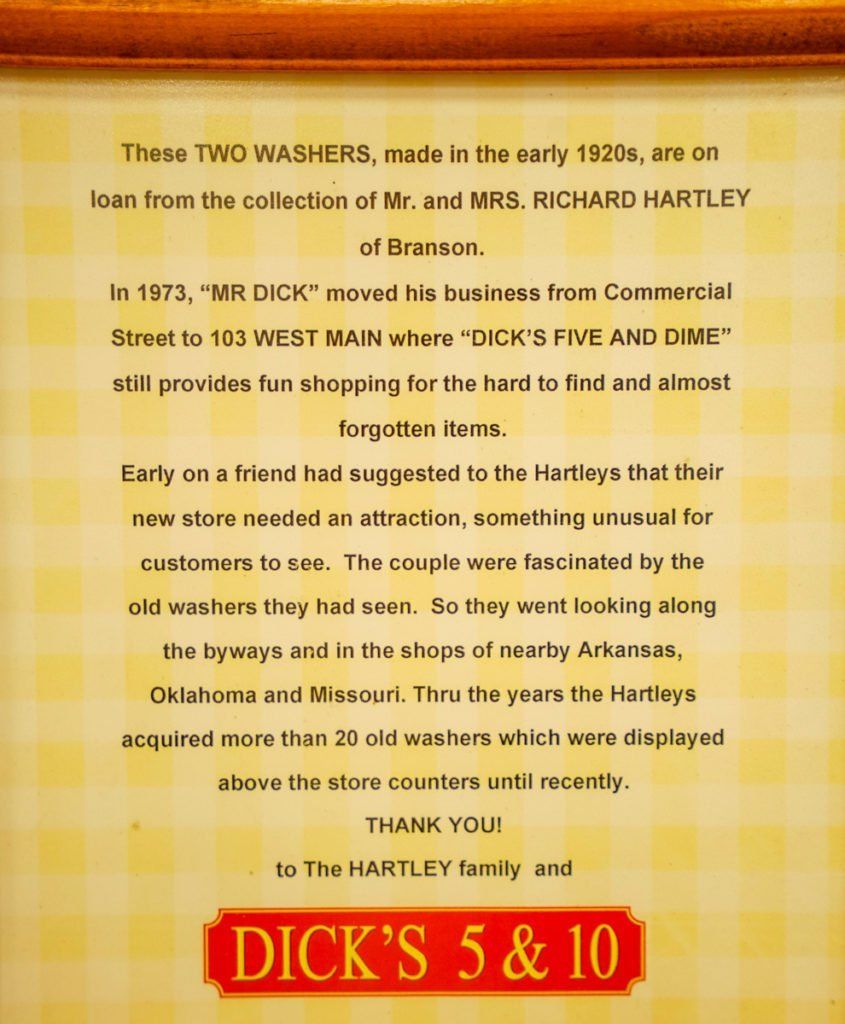 A framed, light yellow checkered plaque describing the history of old washers at Dick's 5 & 10 store in Branson.