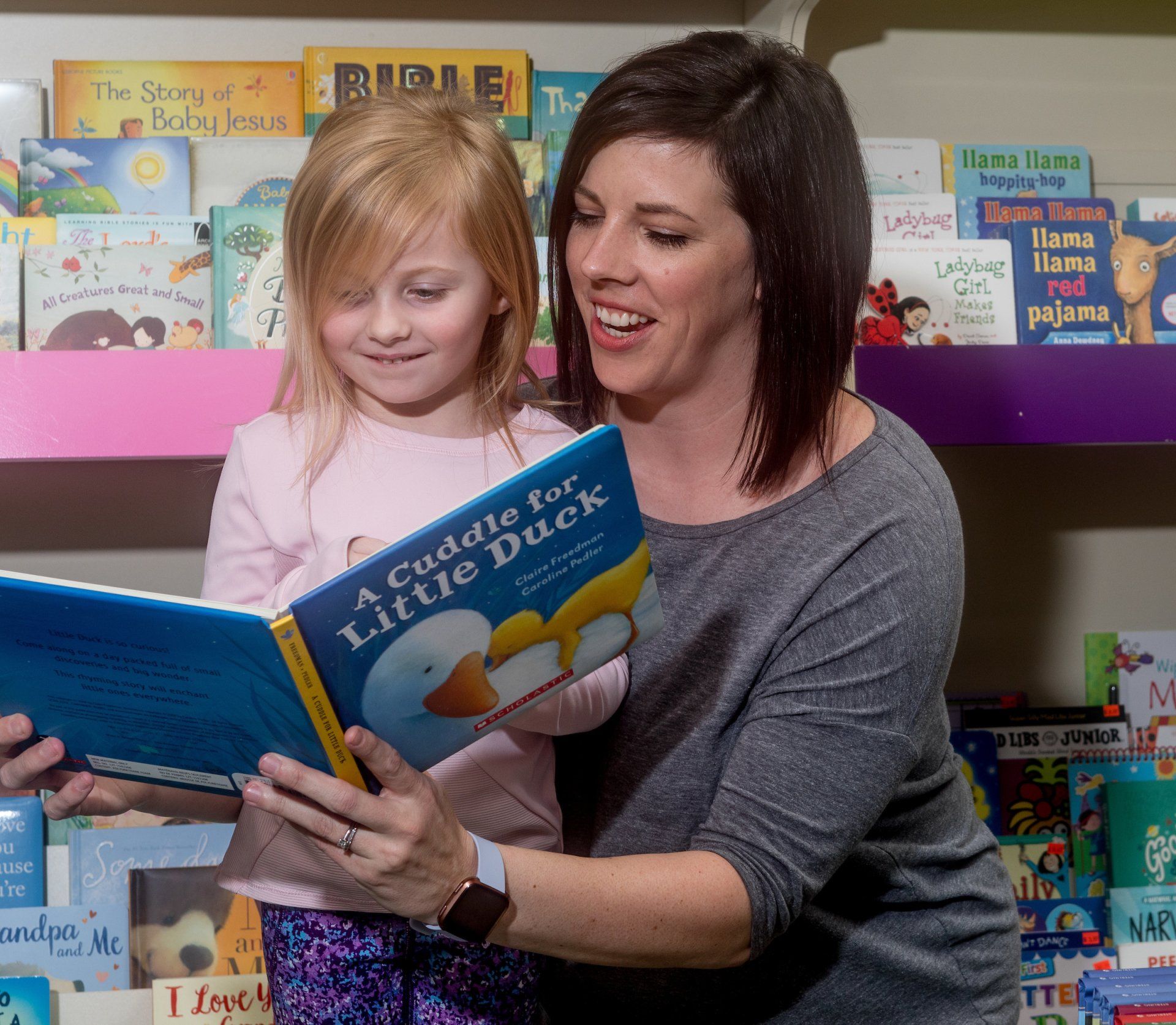 A person and child look at a book titled 