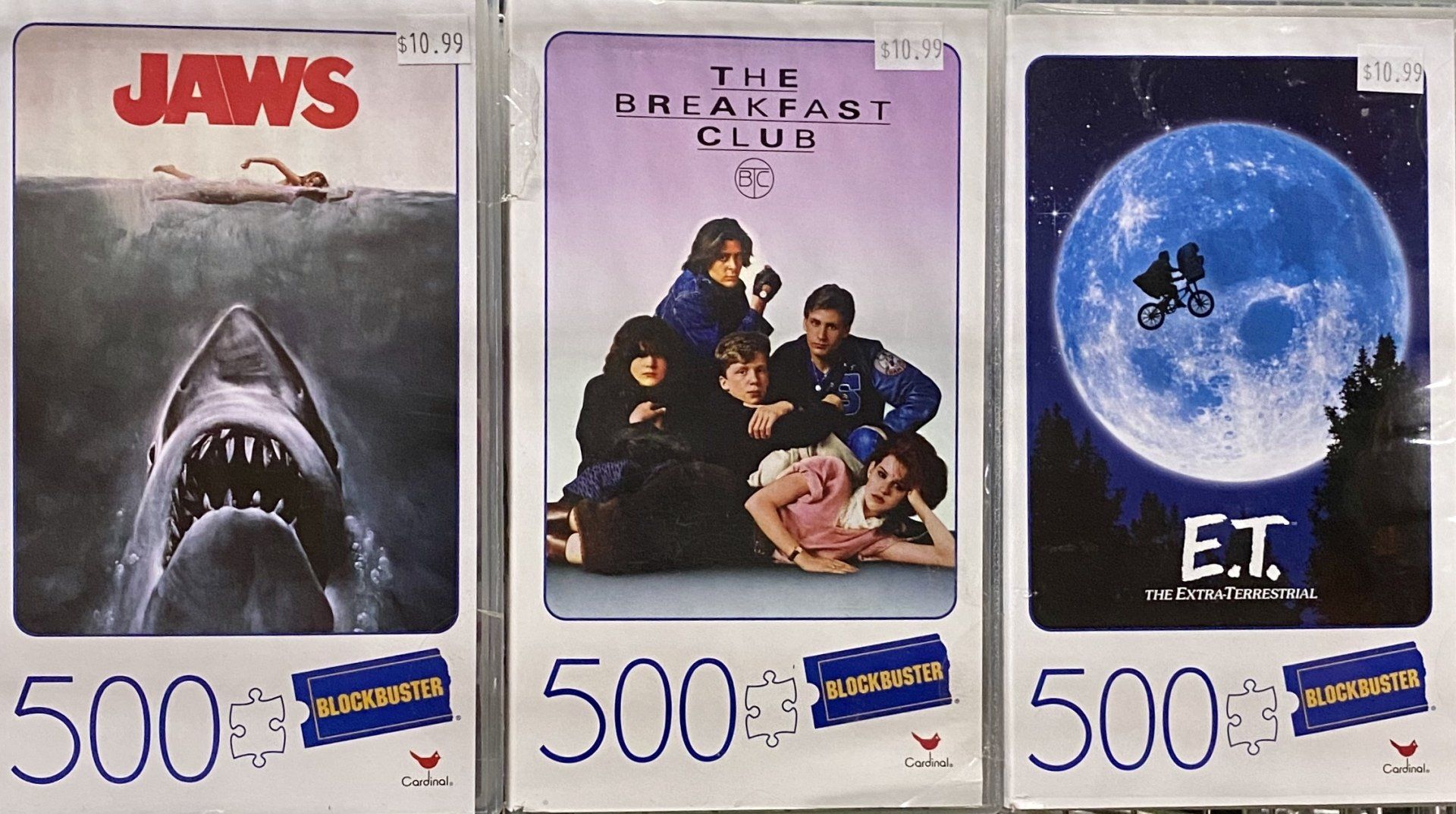 Three 500-piece movie-themed jigsaw puzzles: Jaws, The Breakfast Club, and E.T., displayed side-by-side on store shelves.