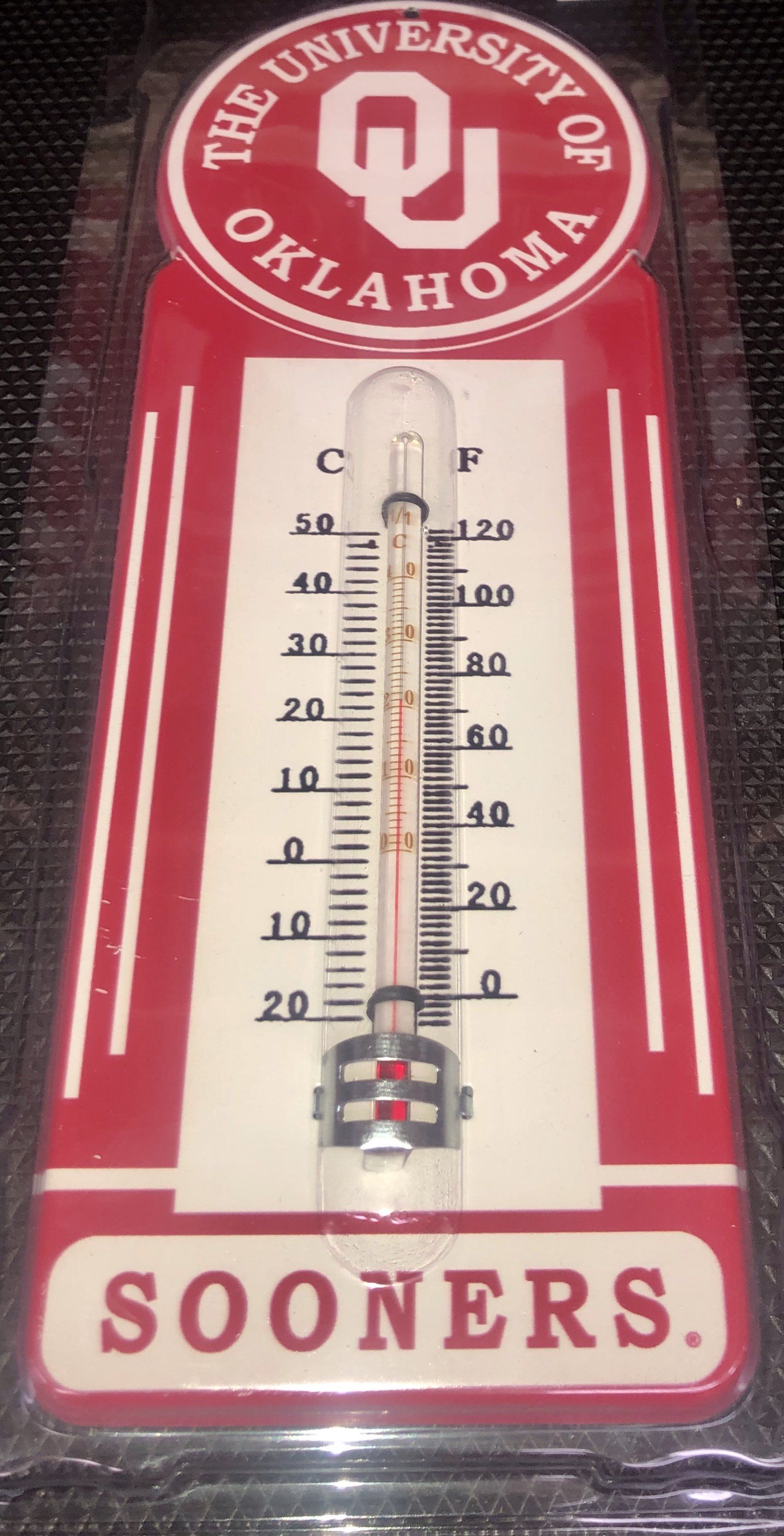 A University of Oklahoma Sooners red-and-white wall thermometer in plastic packaging.