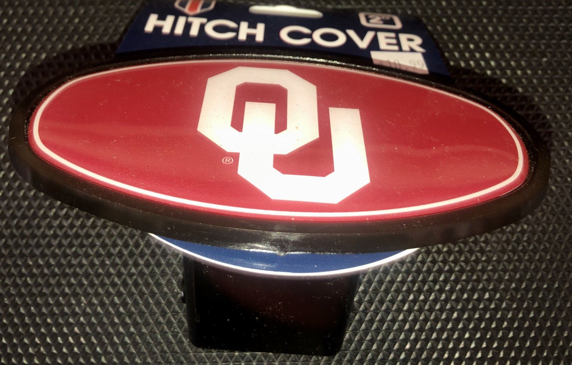 An oval University of Oklahoma Sooners hitch cover with a white 