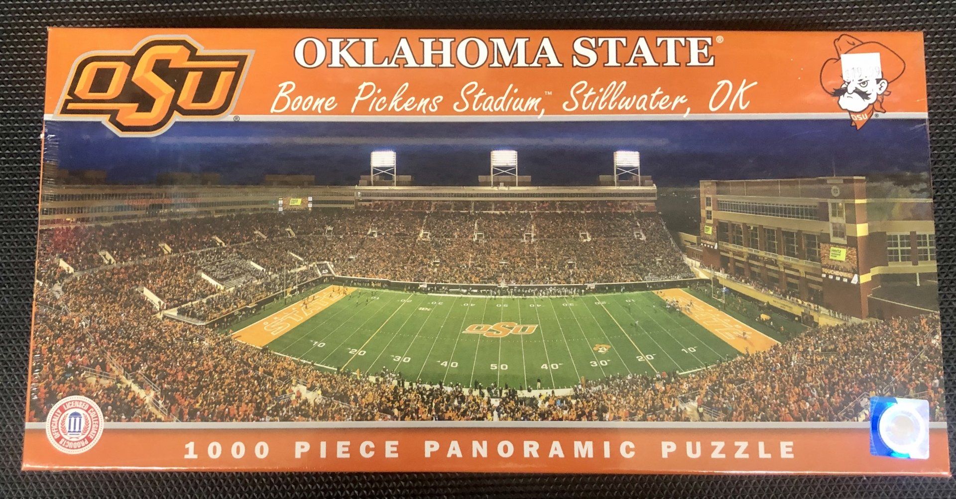 A 1000-piece panoramic puzzle box featuring an aerial night view of Boone Pickens Stadium at Oklahoma State University.