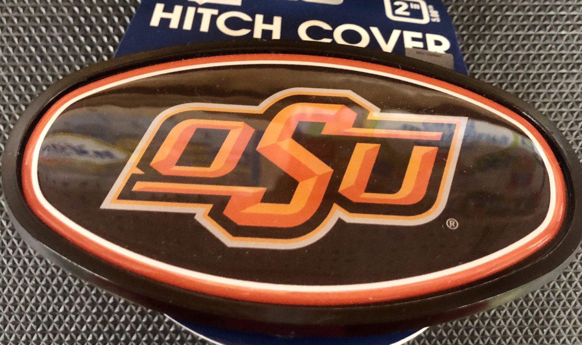 An oval Oklahoma State University hitch cover with an orange and white 