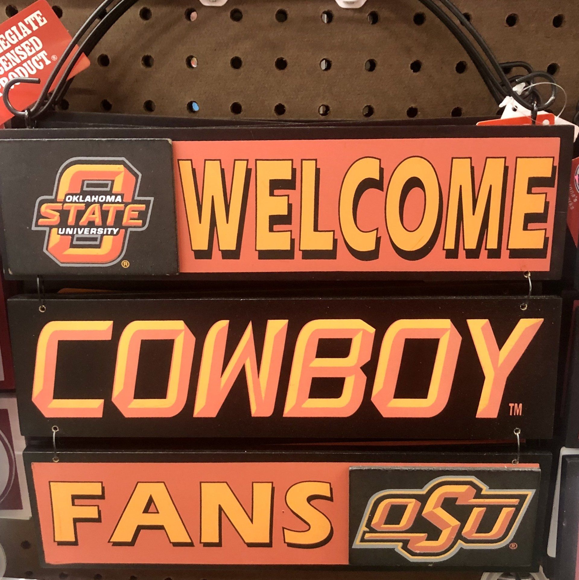 Three hanging, rectangular signs in orange and black that read 